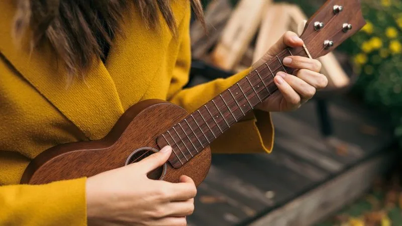 Woman playing a G ukulele chord